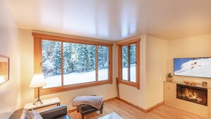 A cozy living room with a fireplace, a sofa, a small table, and a TV. - Modern 1 bedroom in Ski Trails by RedAwning (Truckee)
