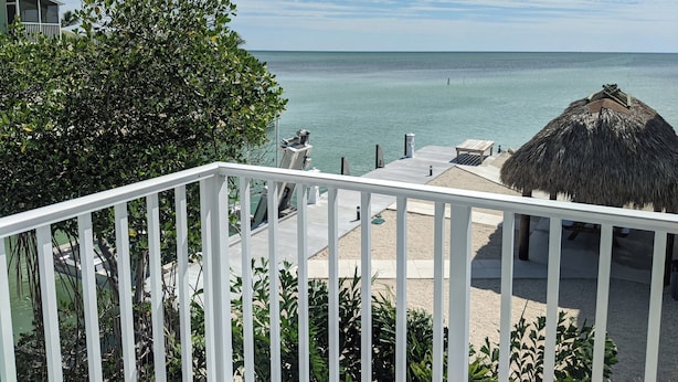 A balcony with a view of the sea, a thatched roof structure, and a white railing. - 2/2 Ocean, Canal, Dock- Fall Getaway @ Casita Mar! (Marathon)