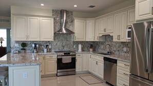 A modern kitchen with white cabinetry, a stainless steel range, and a marble backsplash. - 2/2 Ocean, Canal, Dock- Fall Getaway @ Casita Mar! (Marathon)