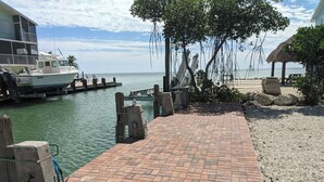 A waterfront dock with a brick walkway leading to a building with a thatched roof. - 2/2 Ocean, Canal, Dock- Fall Getaway @ Casita Mar! (Marathon)