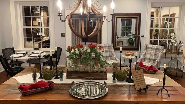 A dining area with a wooden table, chairs, a chandelier, and floral centerpieces. - Historic Boyd Harvey House and Grounds 2 Bedroom Home by RedAwning (Knoxville)