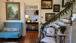 A living room with a blue sofa, a chair, a staircase, and a dining area in the background. - Historic Boyd Harvey House and Grounds 2 Bedroom Home by RedAwning (Knoxville)