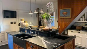 Une cuisine moderne dotée d’un îlot central, de deux éviers, d’un éclairage suspendu et de meubles de rangement en bois.