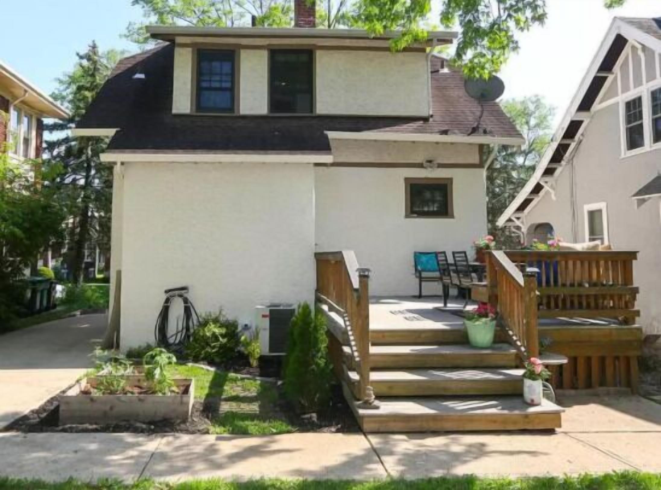 A two-story house with a small porch, a staircase, and a garden area.