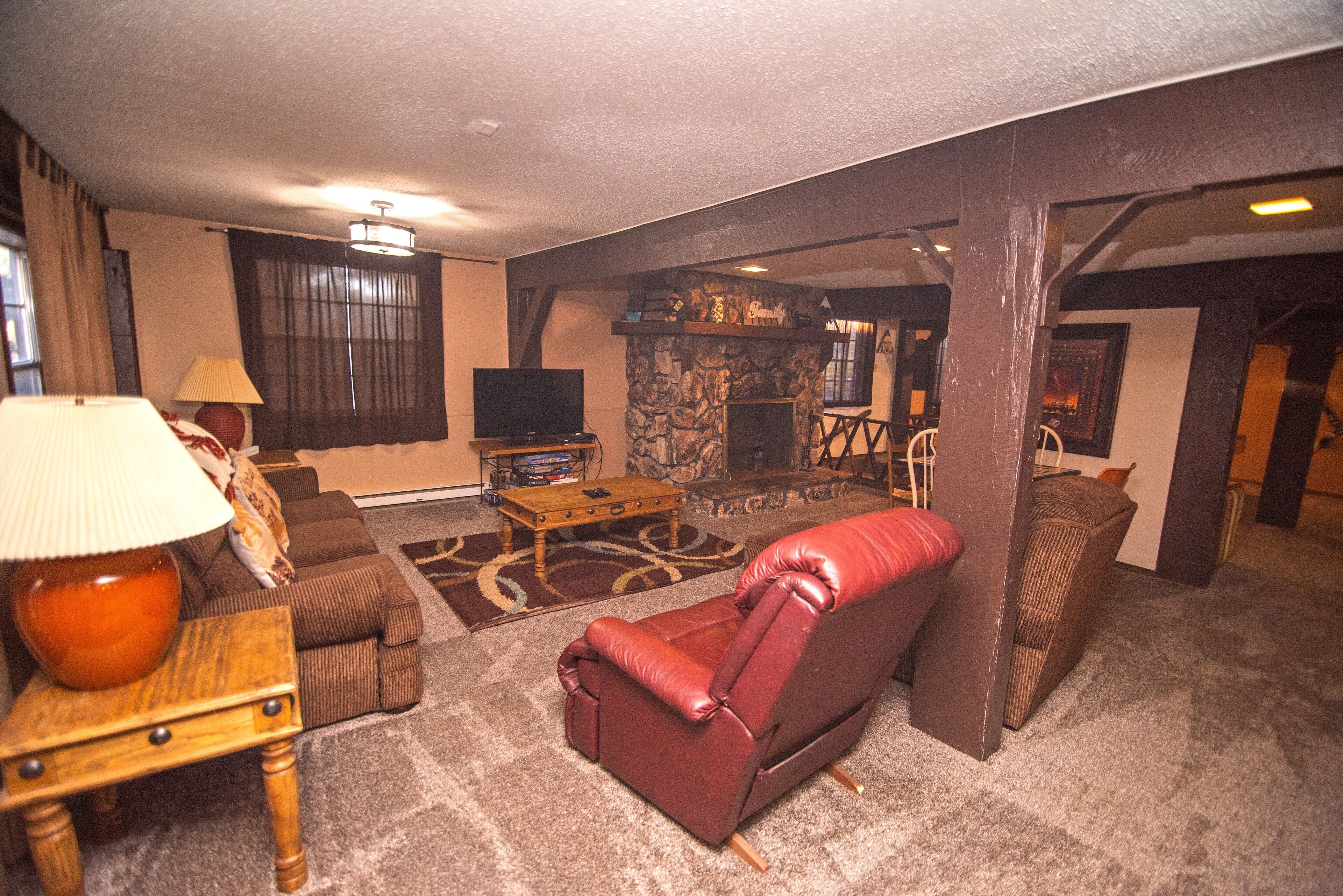 Una sala de estar acogedora con un sofá de cuero, un televisor, una chimenea de piedra y una mesa de centro de madera.