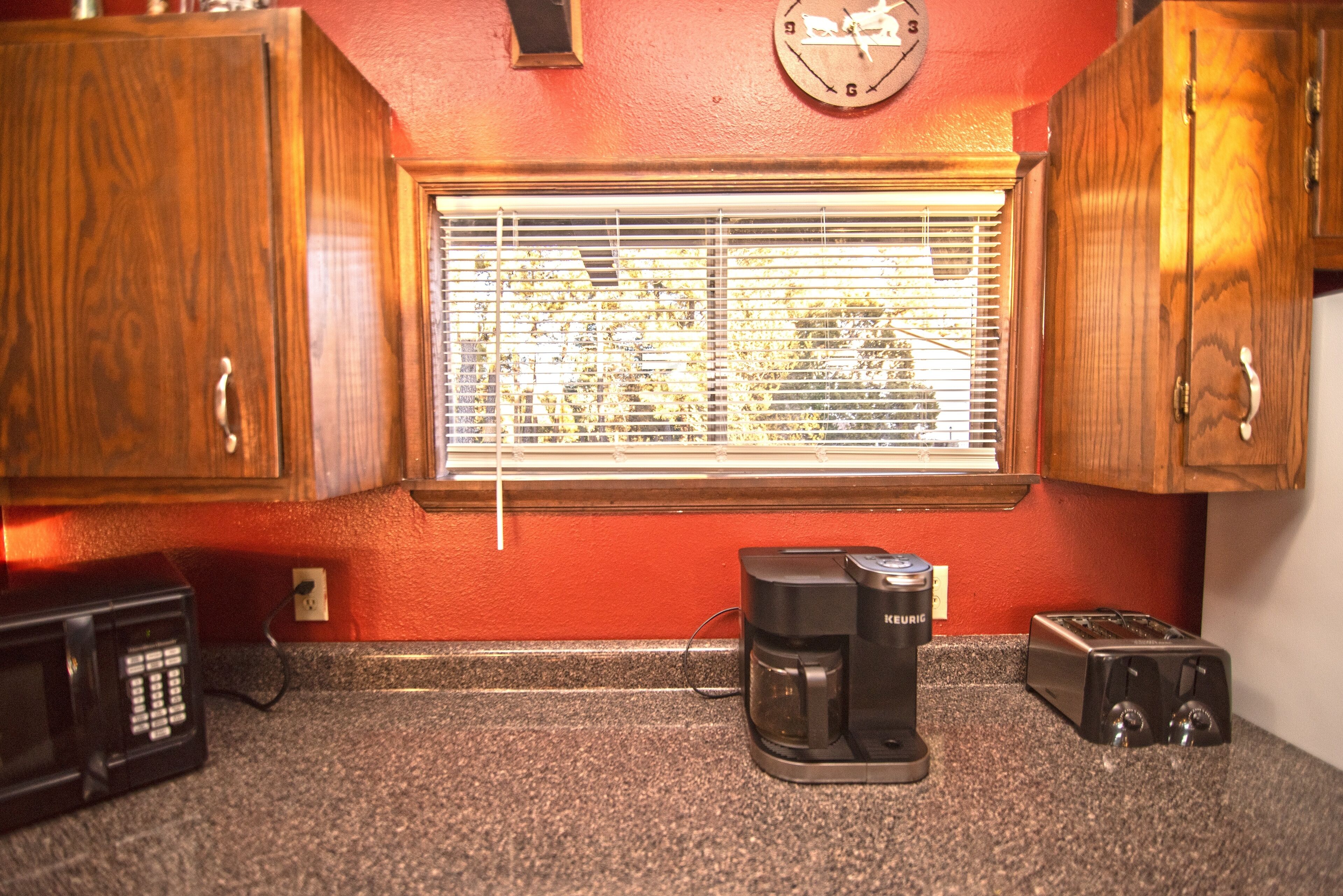 A kitchen with wooden cabinets, a coffee maker, a toaster, and a clock on the wall.