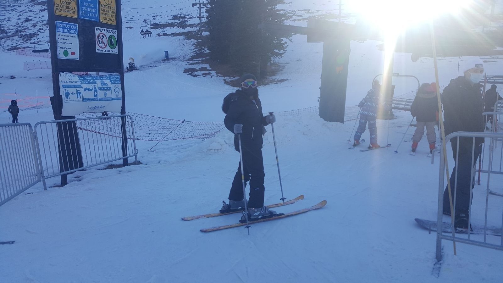 Una persona esquiando en una pendiente nevada con un telesilla al fondo.