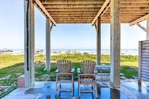 Ein hölzerner Strandpavillon mit zwei Adirondack-Stühlen, die auf den Ozean ausgerichtet sind.