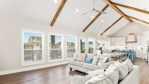 Un salón espacioso con techos altos, vigas de madera y ventanas grandes.