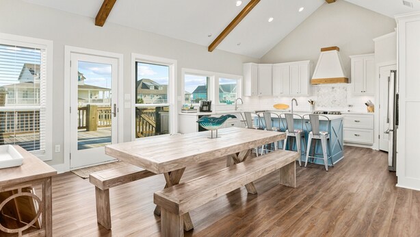 Una cocina amplia con vigas de madera, armarios blancos y una isla grande con taburetes de bar.