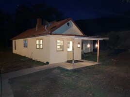 A single-story house with a sloped roof, a covered porch, and a small front yard.