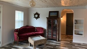 A living room with a red sofa, a wooden coffee table, a cabinet, and a ceiling fan.