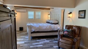 A bedroom with a bed, a chair, a dresser, and a window.