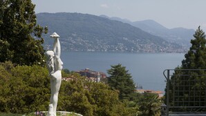 A statue in a garden with a view of a lake and mountains in the background. - Wonderful private villa with hot tub, sauna, private pool, WIFI, A/C, TV, patio and panoramic view (Baveno)