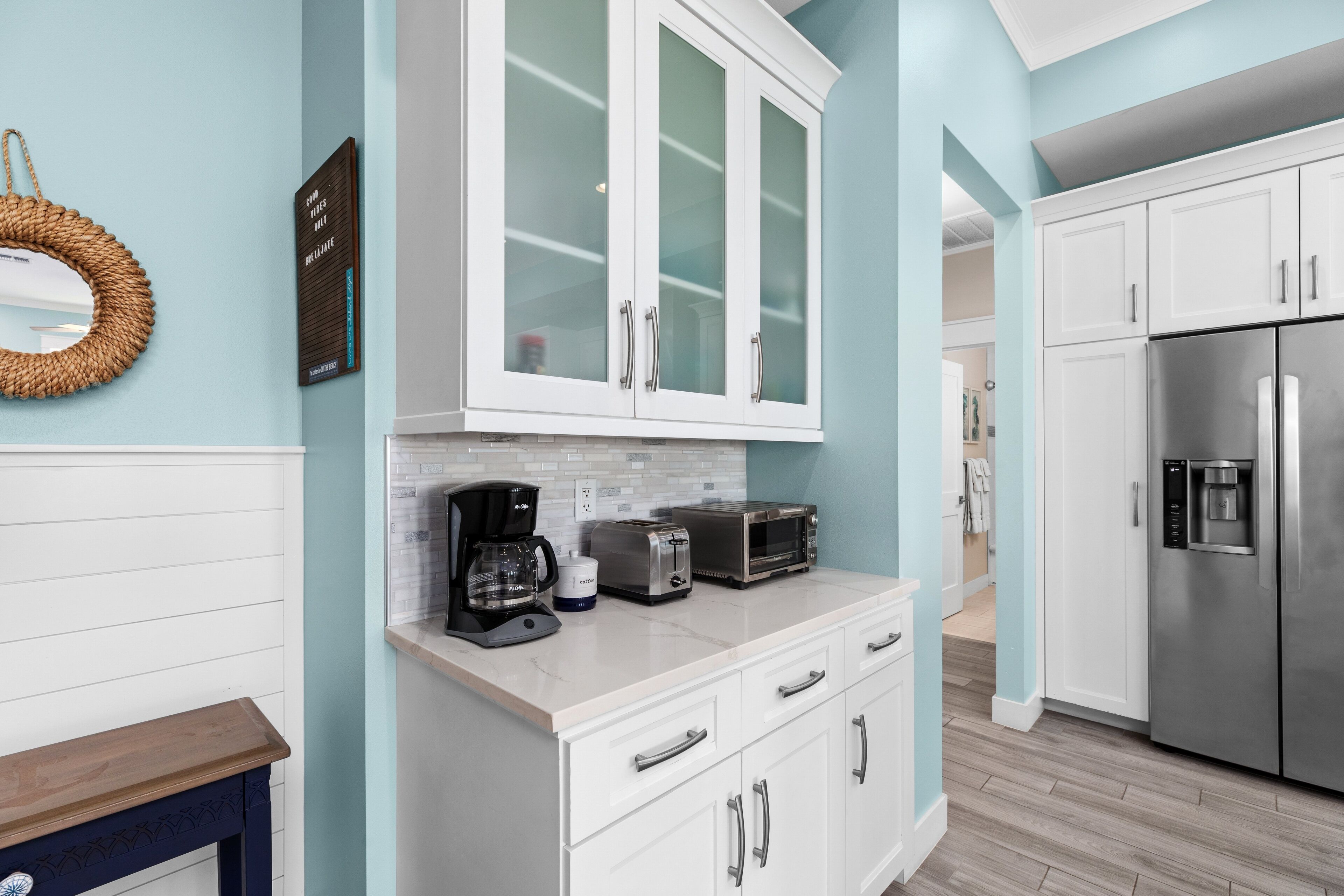 A modern kitchen with white cabinets, a coffee maker, a toaster, and a stainless steel refrigerator.