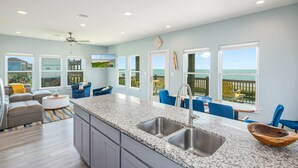 Eine moderne Küche mit Granit-Arbeitsplatten, einer doppelten Spüle und Meerblick durch große Fenster.