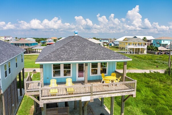 A coastal house with a deck, yellow chairs, and a clear view of the ocean. - 1 Naut On Call 3 Bedroom Home by RedAwning (Port Bolivar)