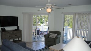 A living room with a sofa, armchair, TV, and a ceiling fan.