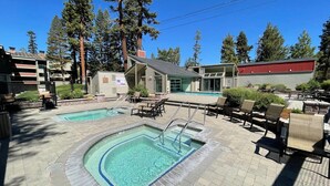 A pool area with two pools, lounge chairs, and a building with a 'For Sale' sign. - Summer Hikes From Out Your Front Door and Free Village Gondola! by RedAwning (Mammoth Lakes)