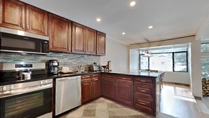 A modern kitchen with wooden cabinets, stainless steel appliances, and a large window providing natural light. - Summer Hikes From Out Your Front Door and Free Village Gondola! by RedAwning (Mammoth Lakes)