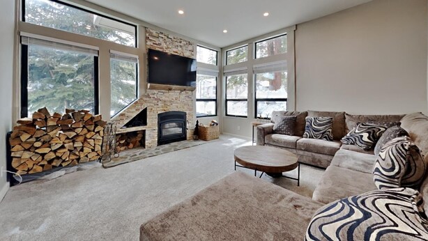 A modern living room with a stone fireplace, a large window, and a cozy sofa. - Summer Hikes From Out Your Front Door and Free Village Gondola! by RedAwning (Mammoth Lakes)