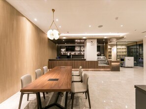 Un intérieur moderne comprenant une table à manger en bois, des chaises, un coin cuisine et un comptoir avec une vitrine.