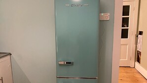 A teal vintage refrigerator in a room with wooden flooring and a white door. - Cottage Just 2 Blocks to Beach and Town (East Tawas)