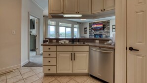 A kitchen with white cabinets, a stainless steel dishwasher, and a stone backsplash. - Panoramic Mountain Range Views! Spacious 2 King BR Chalet w/Garage, Jacuzzi, WiFi & Free Tickets (Sevierville)