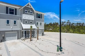 Une maison à deux étages avec un garage, une véranda et une allée pavée de sable.