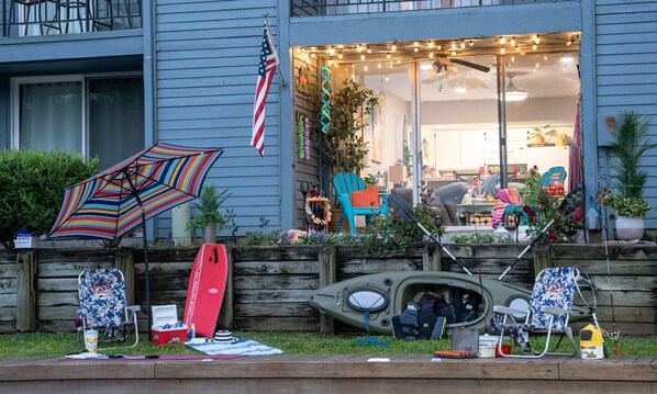 Een huis met een veranda, versierd met tuinmeubilair, een kajak en een surfplank.