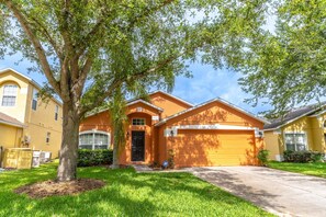 A two-story house with a garage, a tree in the front yard, and a well-maintained lawn.