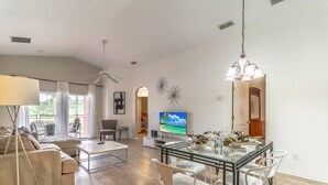 Un amplio salón con sofá, televisor y mesa de comedor.