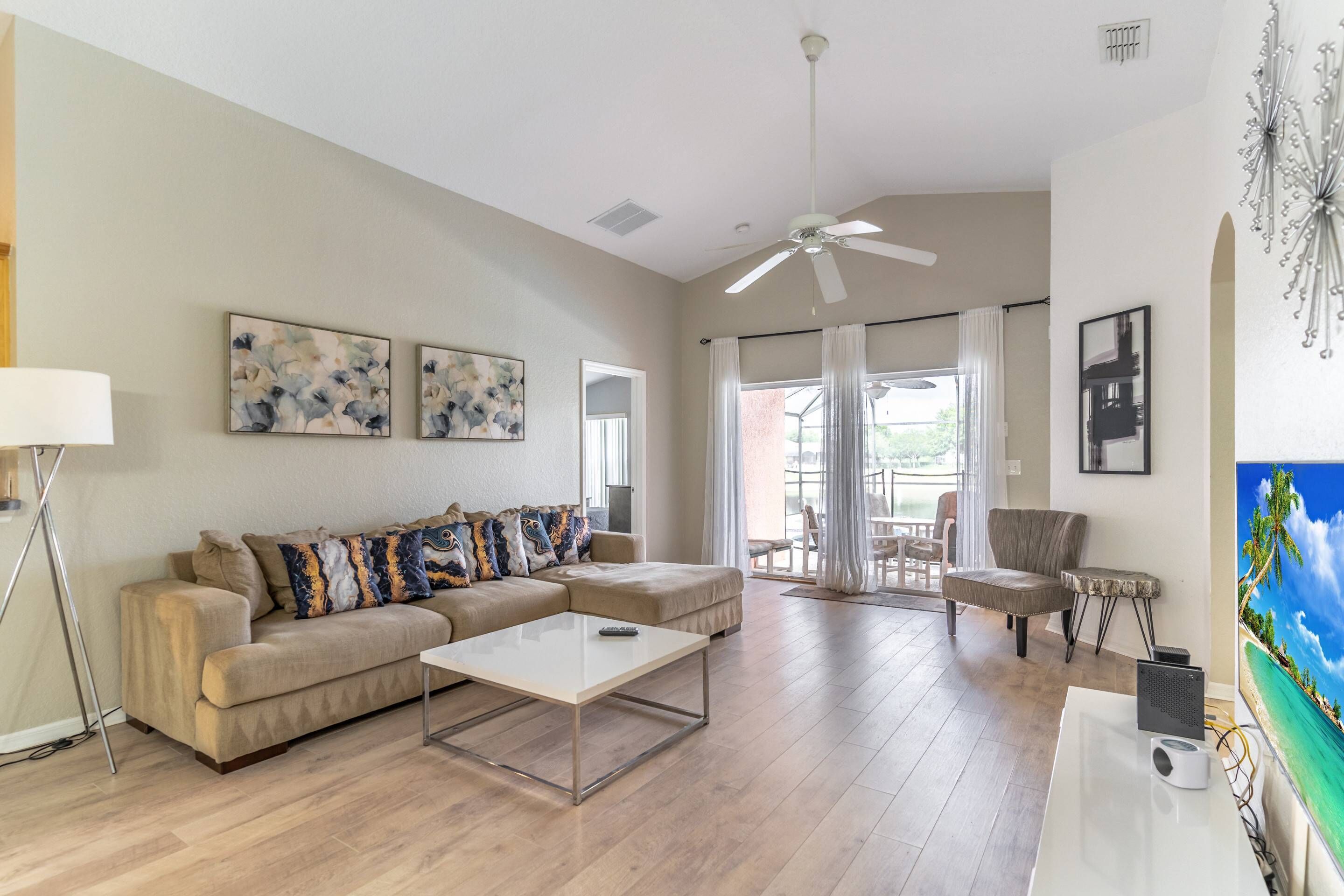 A spacious living room with a beige sectional sofa, a coffee table, and a TV on a stand.