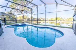 Une piscine intérieure à bords incurvés, entourée d’un espace abrité doté de grandes fenêtres.