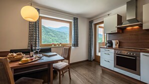 Una cocina moderna con comedor, suelo de madera y vistas a montañas.