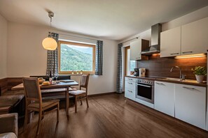 Une cuisine moderne avec un plancher en bois, un coin repas avec un banc et une vue sur l’extérieur.