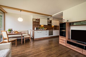 Una cocina moderna con armarios de madera, un comedor con banco, y un mueble para televisor.