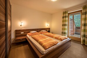 A bedroom with a wooden bed, two bedside tables, a nightstand, and a window with curtains.