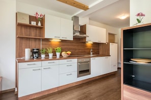Una cocina moderna con armarios blancos, encimera de madera, horno empotrado e iluminación debajo de los armarios.