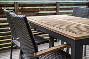 A wooden table with metal chairs on a deck.