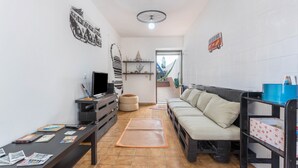 Una sala de estar con un sofá, televisor, una mesa de centro y una estantería.