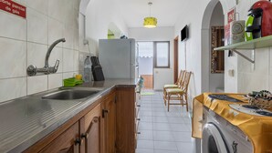 Una cocina con un lavaplatos, un refrigerador, una lavadora y un comedor con sillas.