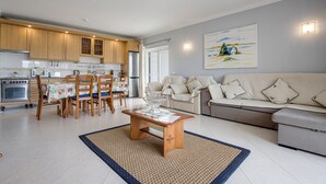 Une cuisine moderne avec des meubles en bois, une table à manger avec des chaises, un canapé et un tableau accroché au mur.
