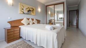 Une chambre à coucher avec un lit, des tables de chevet, un miroir et des œuvres d’art accrochées au mur.