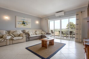 A living room with a sofa, coffee table, and a painting on the wall.