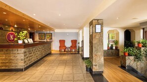 A hotel reception area with a stone counter, two red upholstered chairs, and potted plants. - Sumitel Vista 800m from Mall Road (Darjeeling)