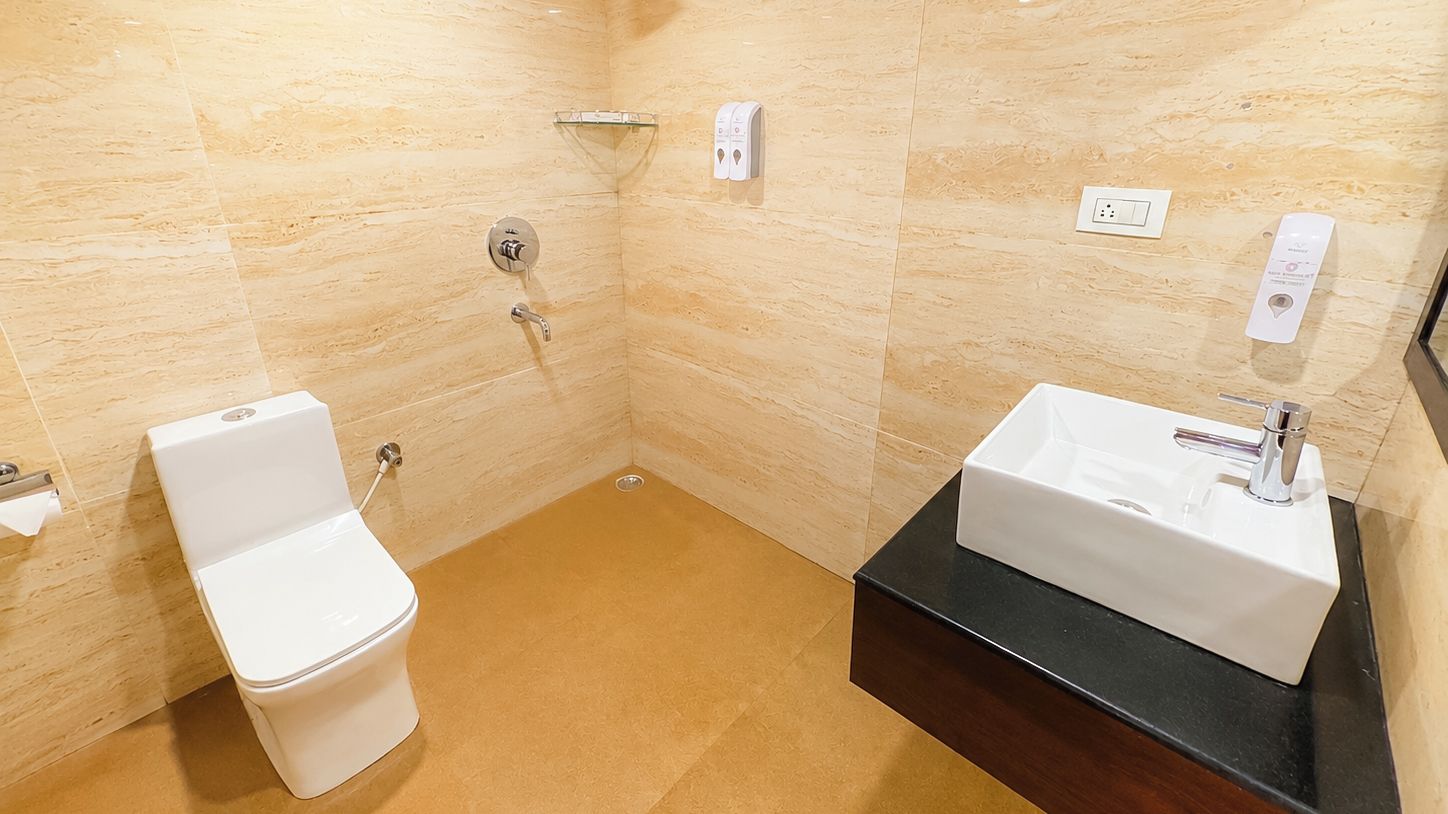 A bathroom with a white toilet, a sink with a black countertop, and a shower area.