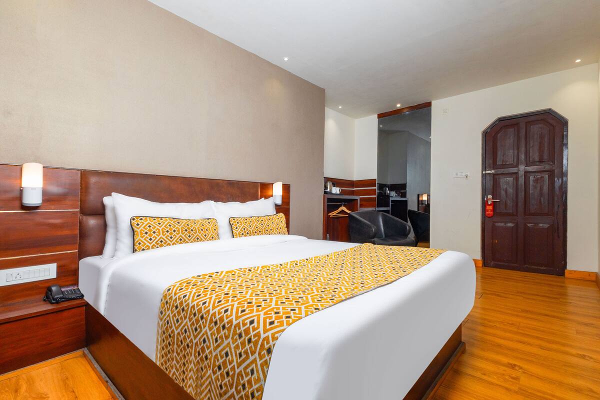 A hotel room with a large bed, wooden headboard, and a wardrobe.