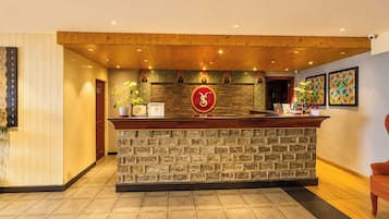 A reception area with a stone counter, wooden ceiling, and a wall-mounted clock.