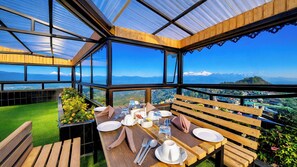 A dining area with a table set for two, overlooking a scenic landscape. - Sumitel Vista 800m from Mall Road (Darjeeling)